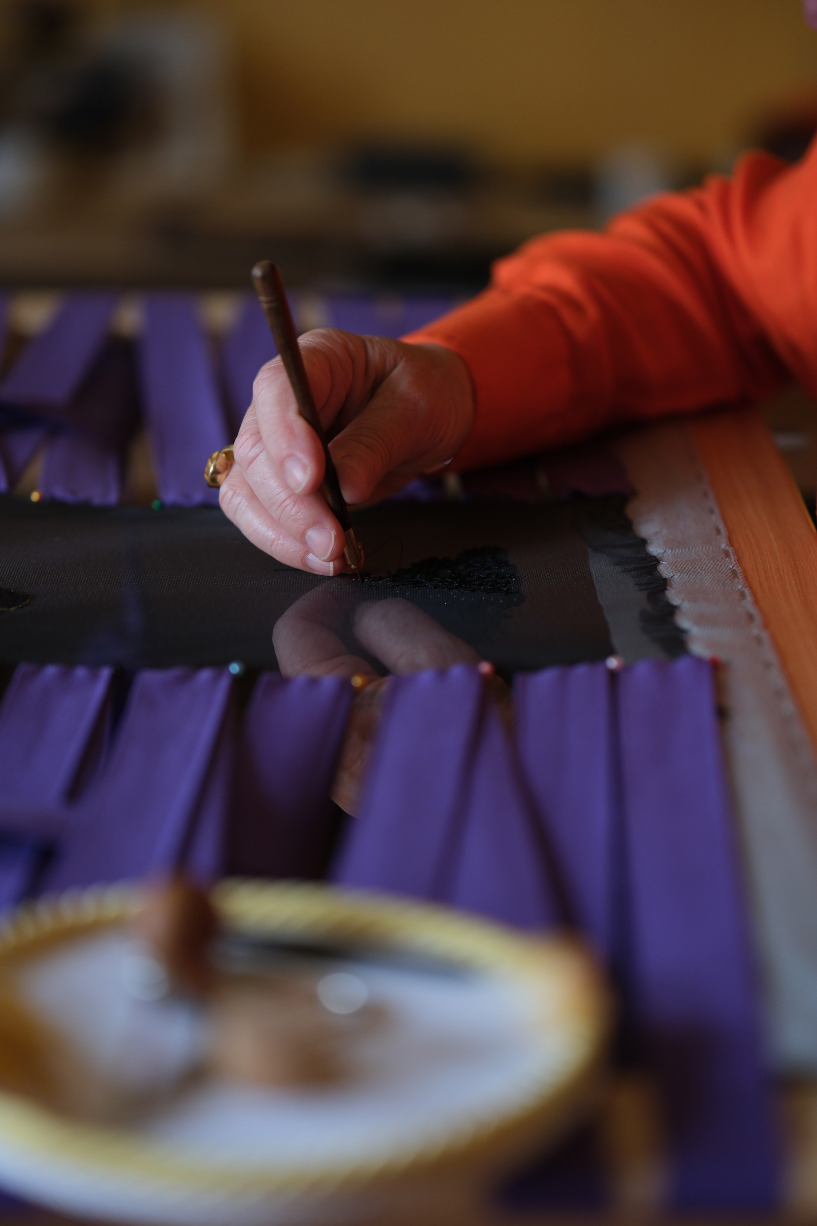 Détail des mains de Ghislaine Bascou brodant une œuvre avec le crochet de Lunéville