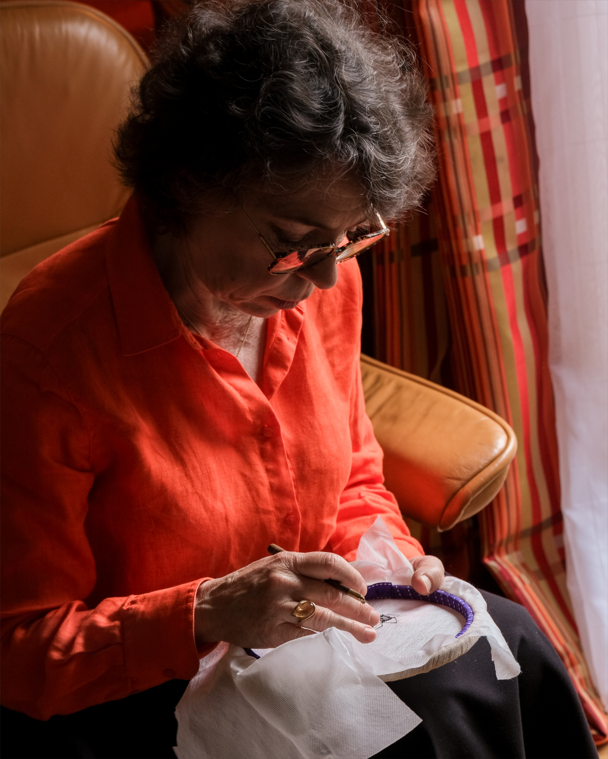 Ghislaine Bascou concentrée sur une création de broderie de Lunéville dans son atelier textile